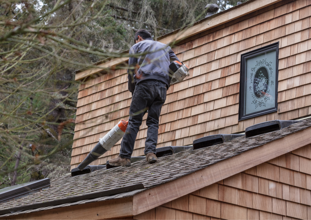 worker using a leaf blower to clear the roof