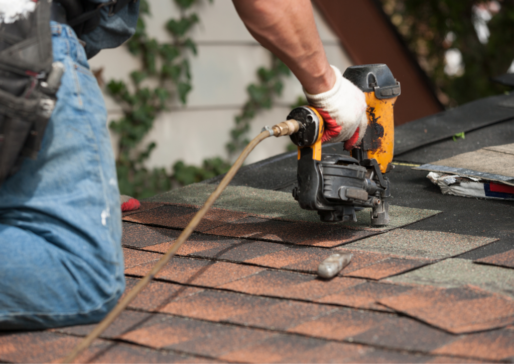 worker installing roof shingles using a nail gun