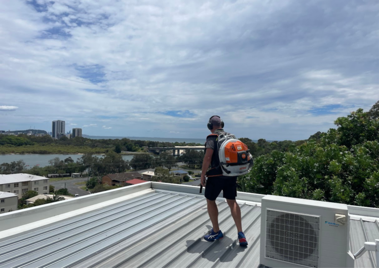 man cleaning commercial roof using a leaf blower