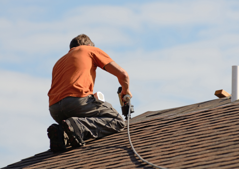 a man doing roof maintenance by installing shingles with a nail gun